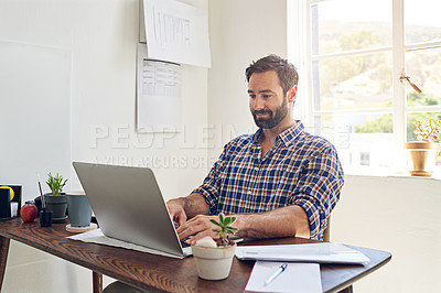 Buy stock photo Shot of a man sitting at a desk working on a laptop