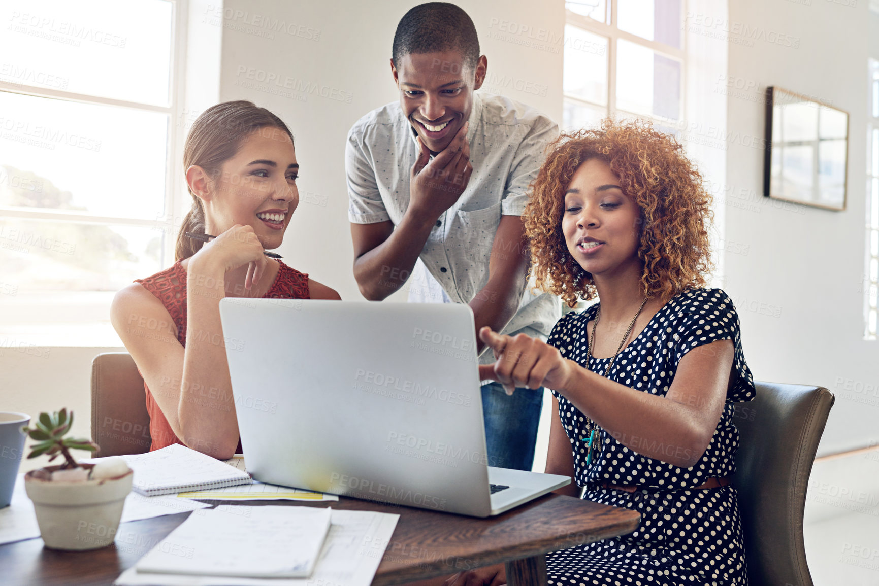 Buy stock photo Shot of a group of colleagues working together on a laptop in an office