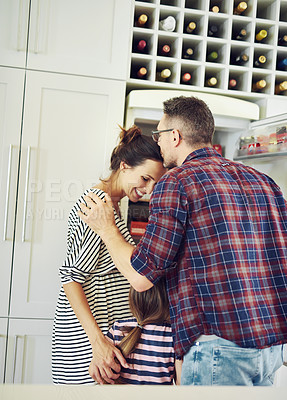 Buy stock photo Shot of a husband lovingly kissing his wife in the kitchen with his family