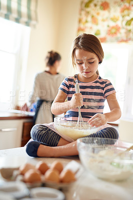 Buy stock photo Shot of a little girl helping her mom bake in the kitchen