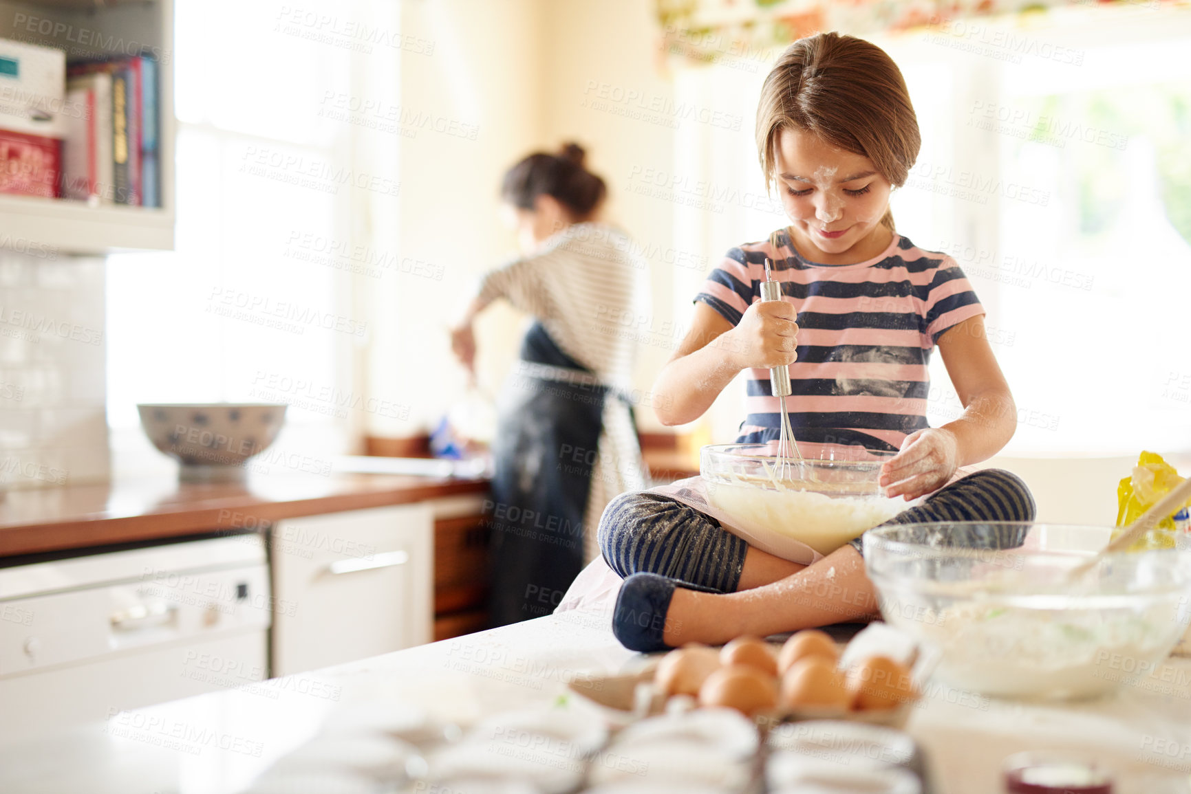 Buy stock photo Shot of a little girl helping her mom bake in the kitchen