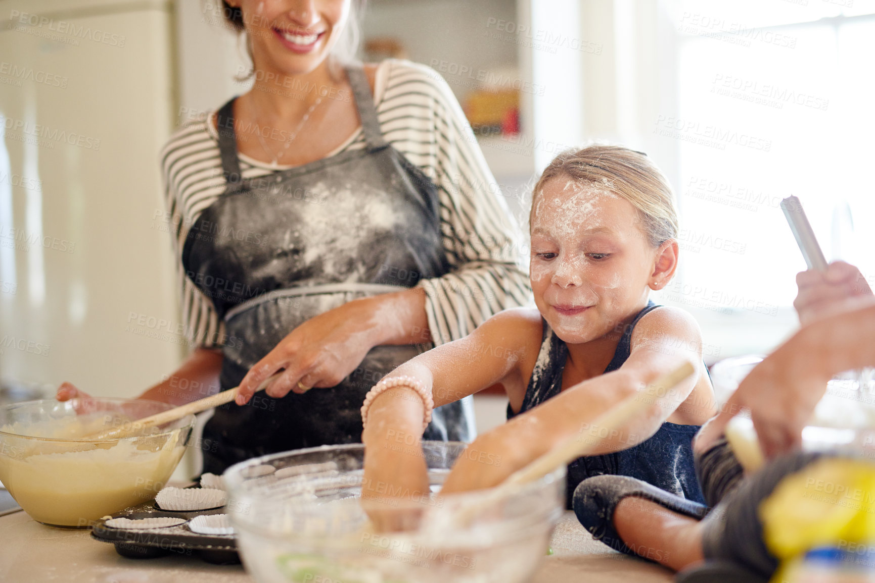 Buy stock photo Shot of two little girls baking with their mother in the kitchen