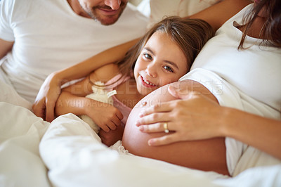 Buy stock photo Shot of a happy little girl lying in bed with her dad and pregnant mother