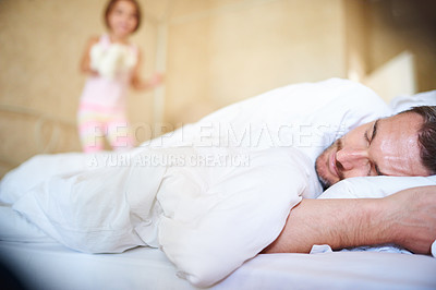 Buy stock photo Shot of a sleeping dad with his little daughter jumping on the end of the bed