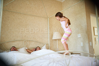 Buy stock photo Shot of a little girl jumping on her parent's bed in the morning