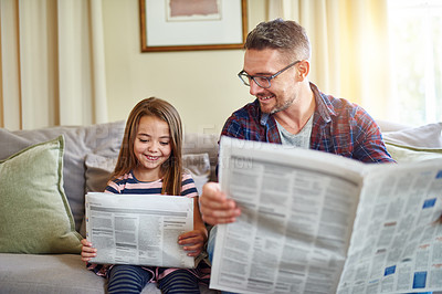 Buy stock photo Shot of a father and daughter reading the newspaper