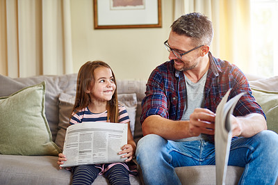 Buy stock photo Shot of a father and daughter reading the newspaper