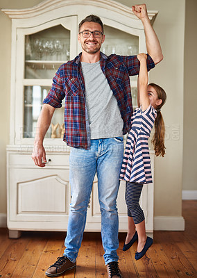 Buy stock photo Shot of a little girl holding on to her father's arm as he lifts her up