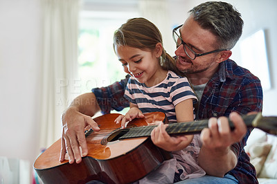 Buy stock photo Shot of a little girl playing the guitar with her father