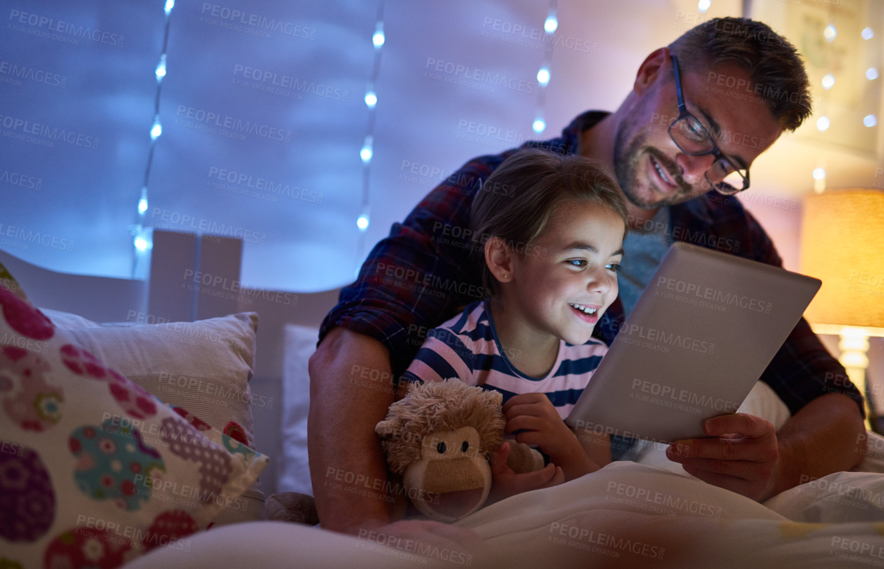 Buy stock photo Shot of a little girl and her father using a tablet before bedtime