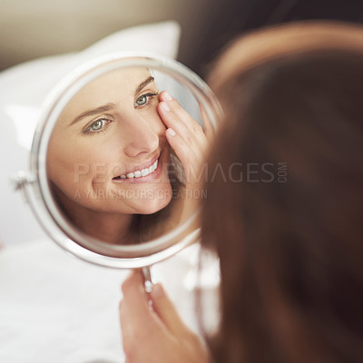 Buy stock photo Shot of an attractive young woman admiring herself in a mirror