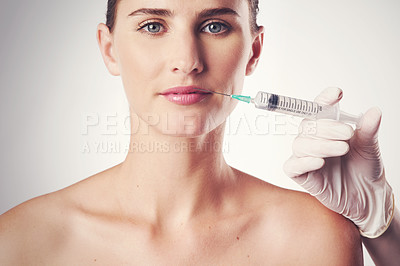 Buy stock photo Studio shot of an attractive young woman getting an injection for cosmetic purposes