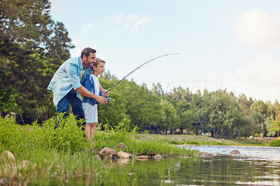 Buy stock photo Shot of a father teching his son how to fish out in the woods