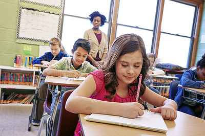 Buy stock photo Shot of a young girl sitting in class with her teacher and classmates blurred in the background