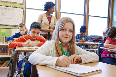 Buy stock photo Shot of a young girl sitting in class with her teacher and classmates blurred in the background