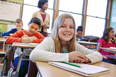 Buy stock photo Shot of a young girl sitting in class with her teacher and classmates blurred in the background