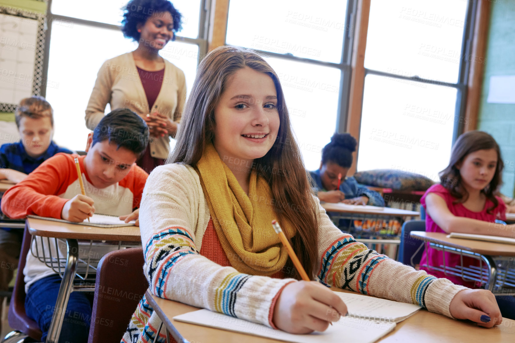 Buy stock photo Shot of a young girl sitting in class with her teacher and classmates blurred in the background