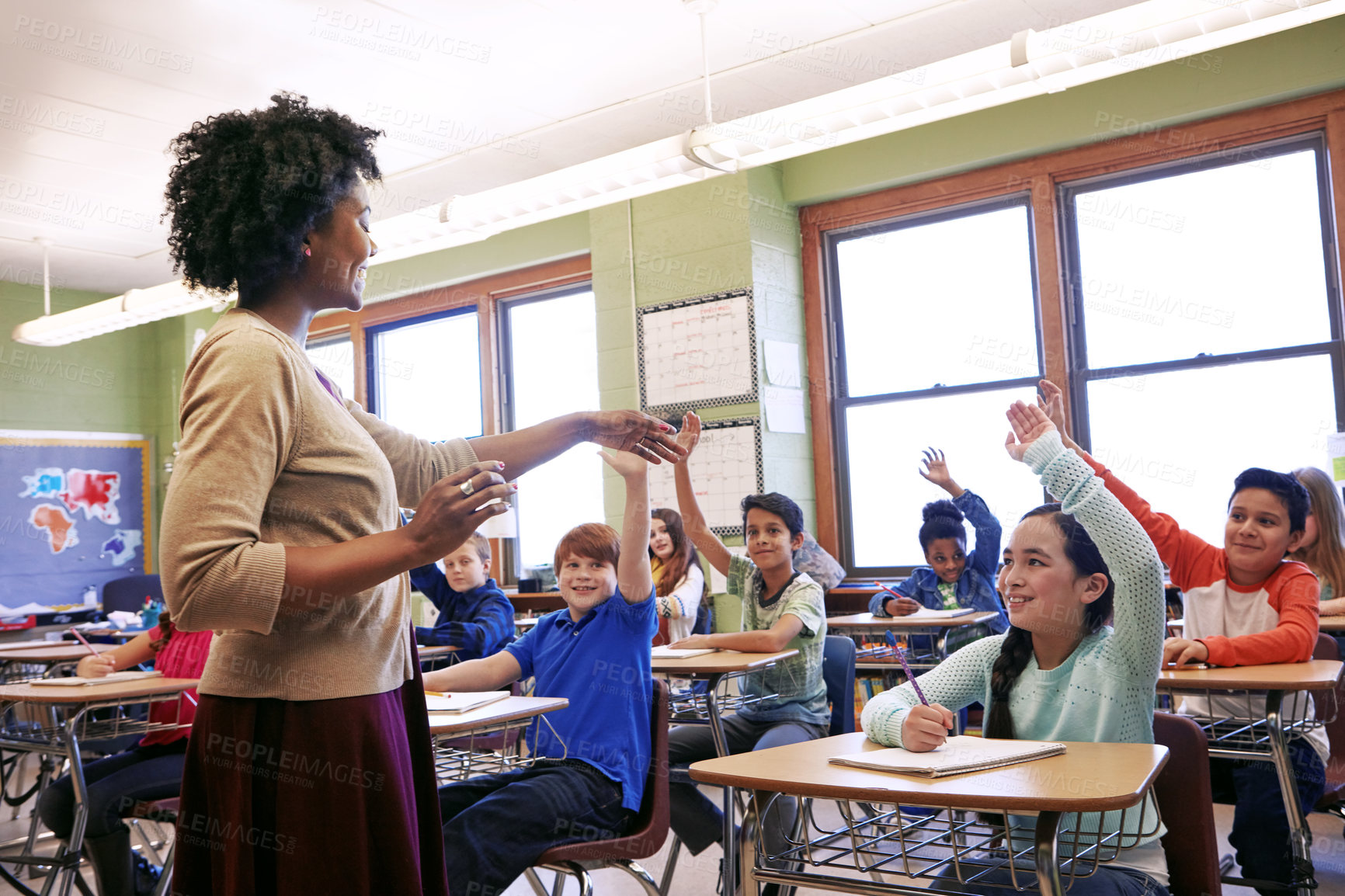 Buy stock photo Shot of a group of children raising their hands to answer their teacher's question