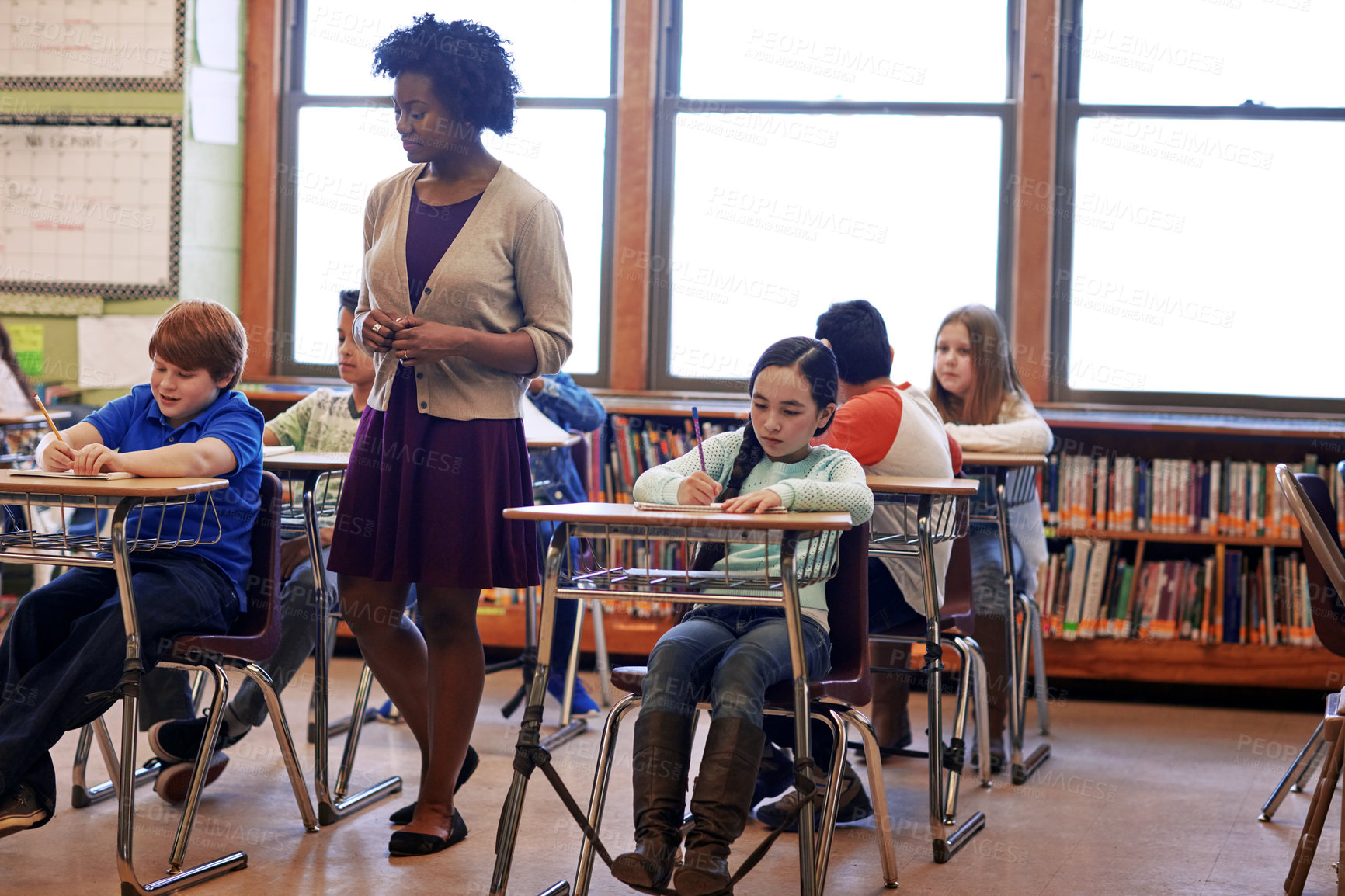 Buy stock photo Kids, classroom and teacher woman at school, focus and education for development, learning and future. School kids, black woman and studying at table in class, diversity and notebook for writing test