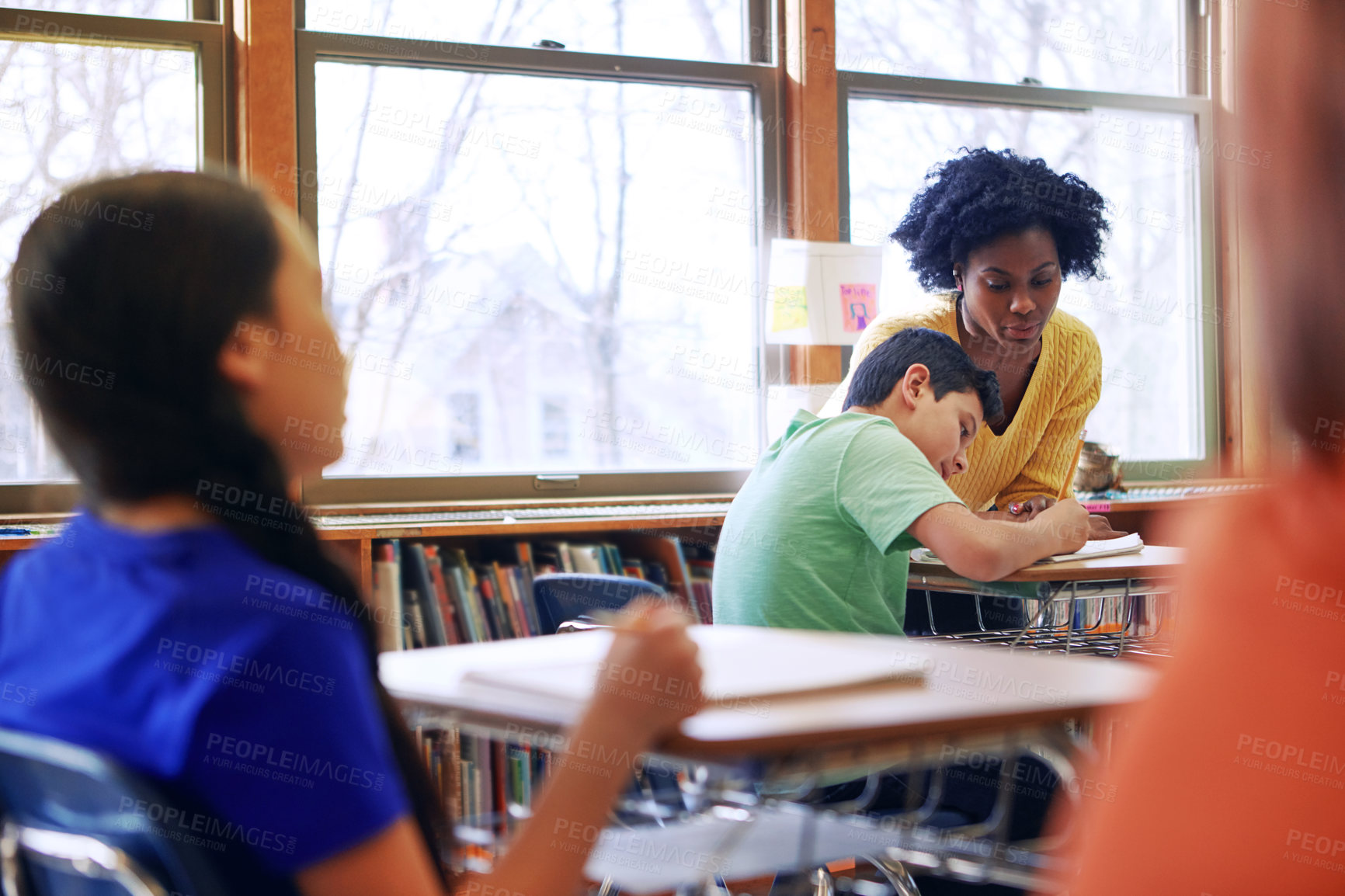 Buy stock photo A young teacher assisting a student with classwork at his desk