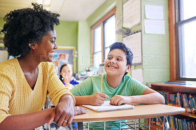 Buy stock photo A young teacher assisting a student with classwork at his desk