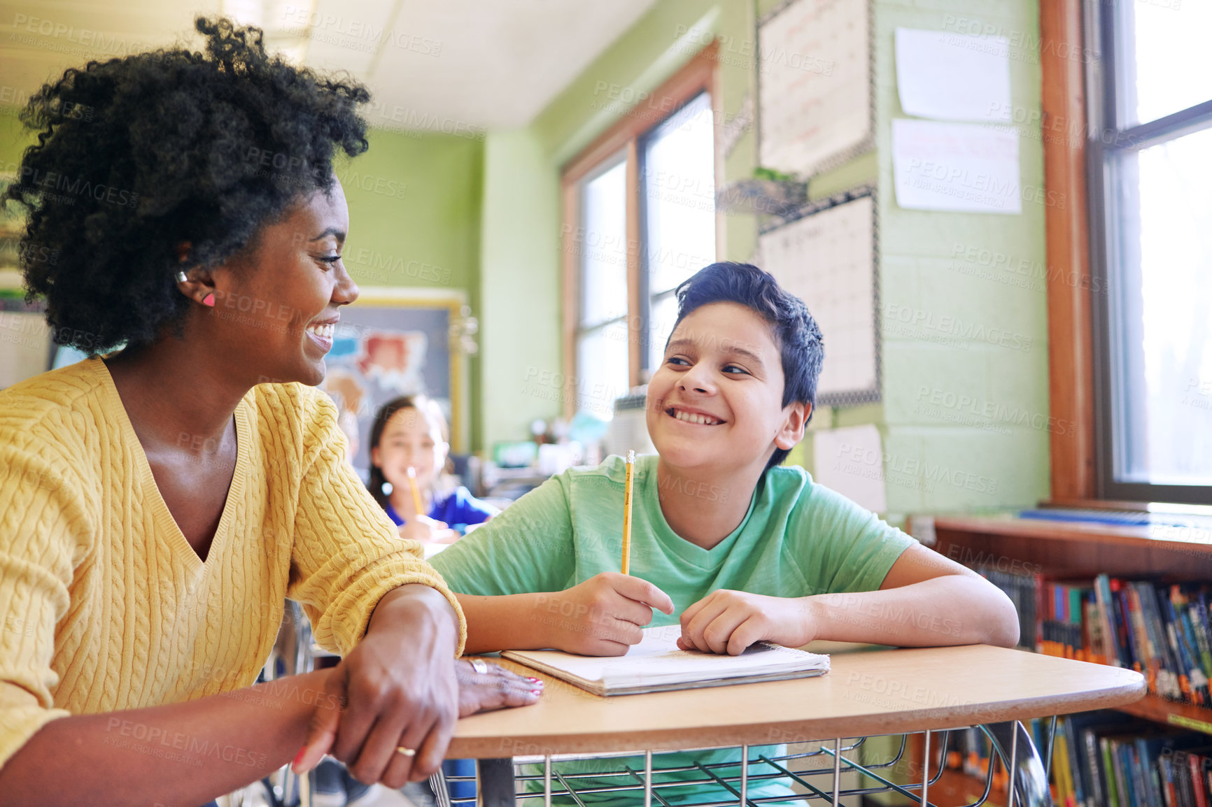 Buy stock photo A young teacher assisting a student with classwork at his desk