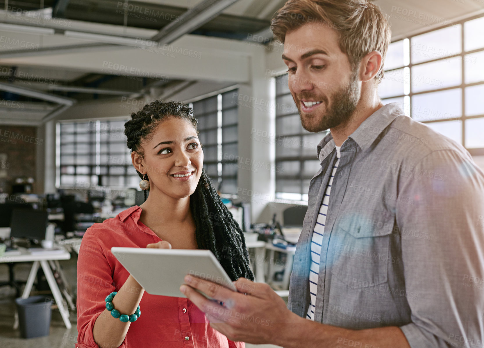 Buy stock photo Shot of two colleagues using a digital tablet together in a modern office