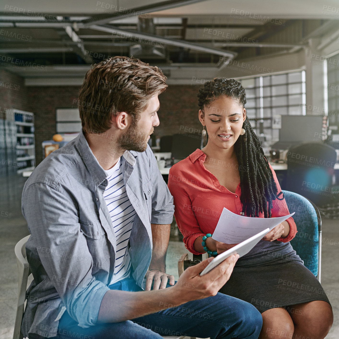 Buy stock photo Shot of two colleagues using a digital tablet during a brainstorming session in a modern office