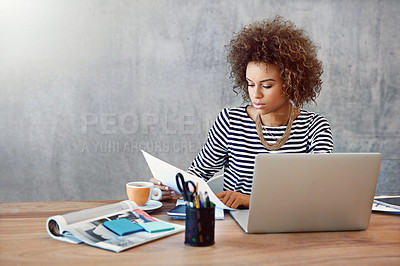 Buy stock photo Shot of a young woman working on a laptop and reading paperwork at home