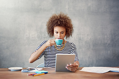 Buy stock photo Shot of a young woman drinking a coffee while working at home with a digital tablet