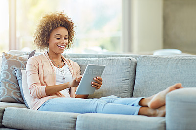 Buy stock photo Shot of a young woman using a digital tablet on a relaxing day at home