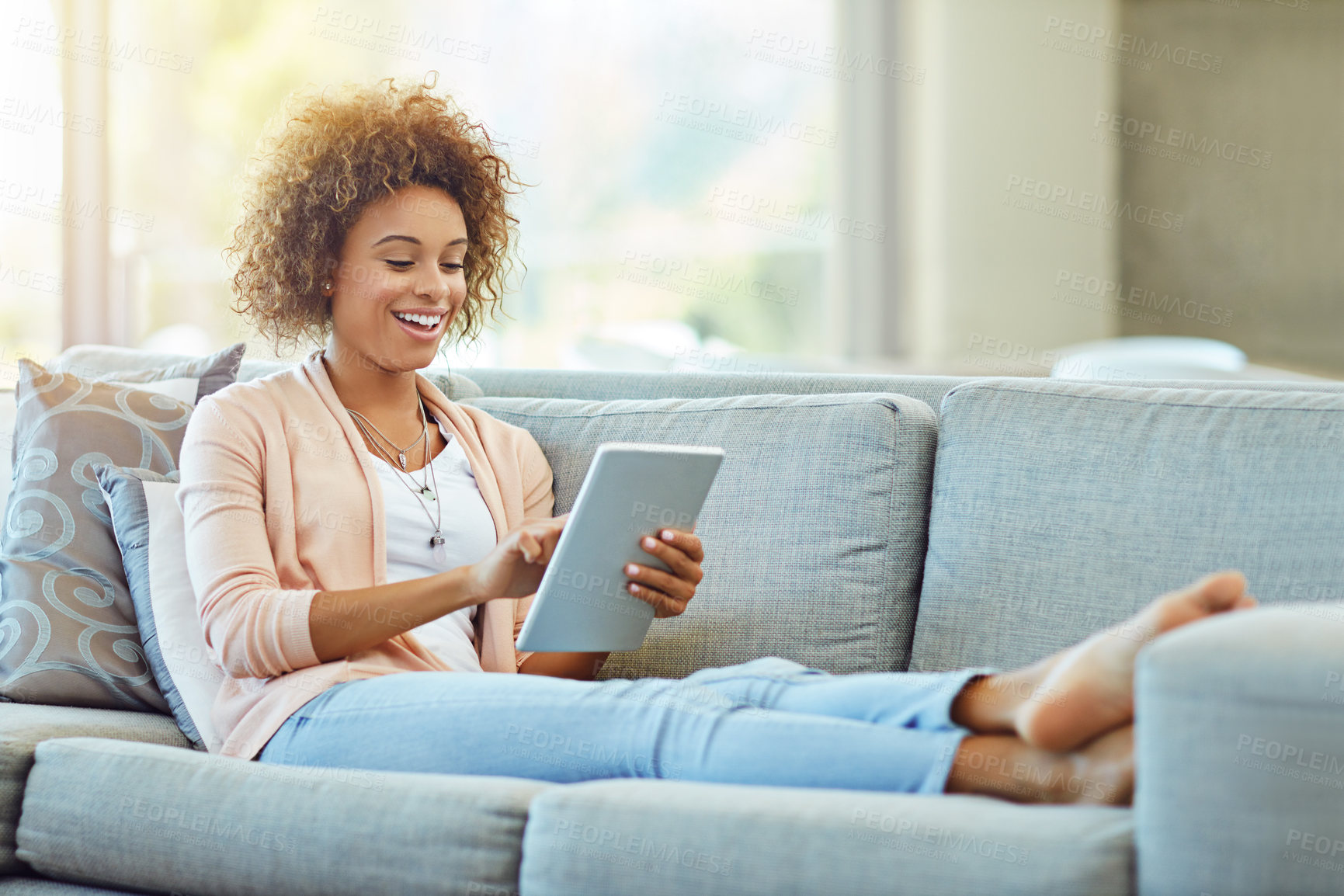 Buy stock photo Shot of a young woman using a digital tablet on a relaxing day at home