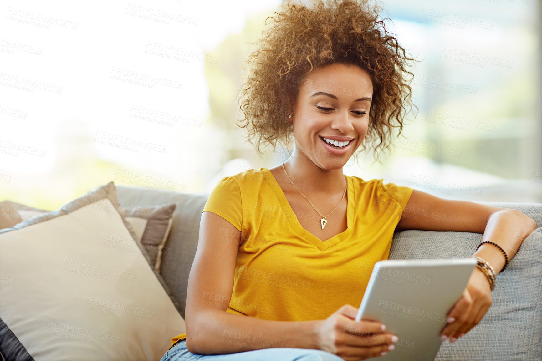 Buy stock photo Shot of a young woman using a digital tablet on a relaxing day at home