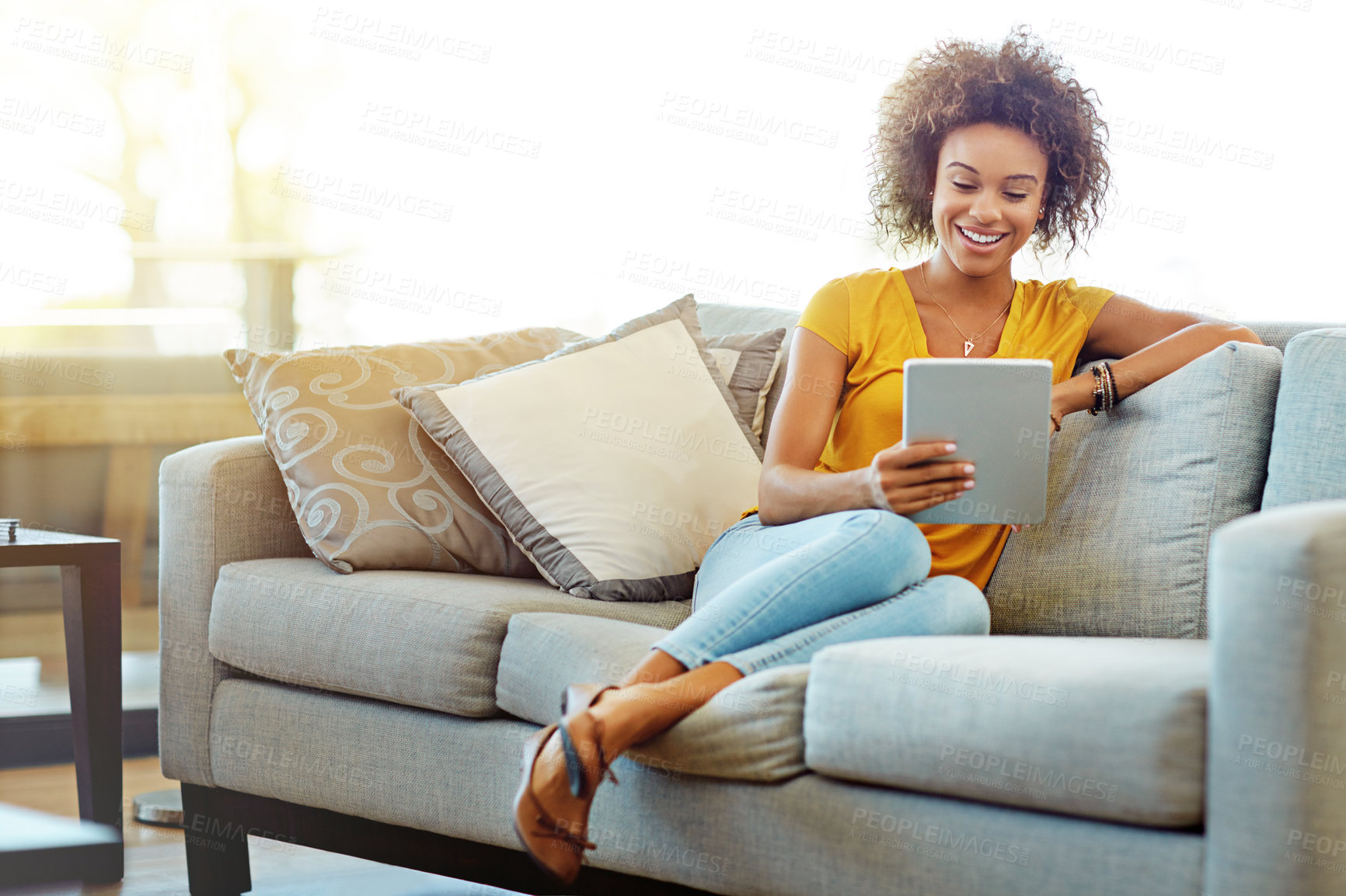 Buy stock photo Shot of a young woman using a digital tablet on a relaxing day at home