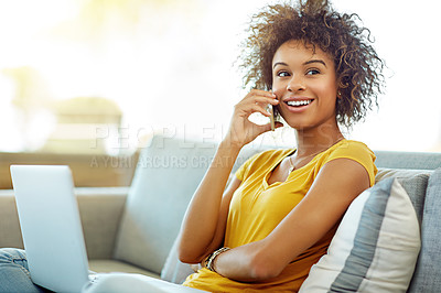 Buy stock photo Shot of a young woman talking on her phone while using a laptop on a relaxing day at home