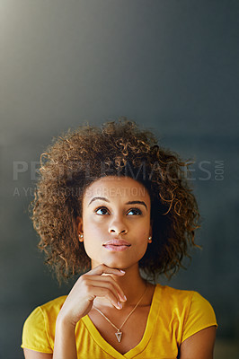 Buy stock photo Studio shot of a thoughtful young woman posing against a dark background