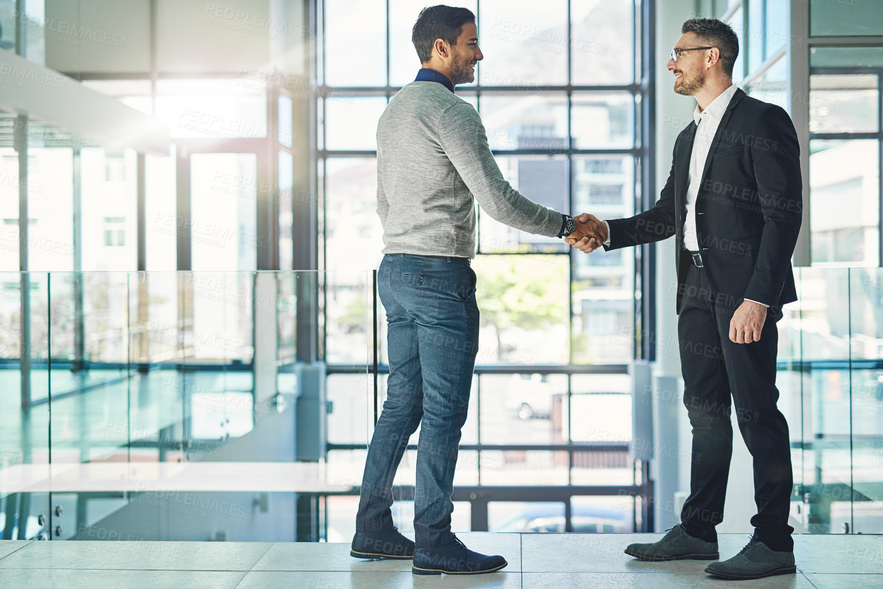 Buy stock photo Shot of two businessmen shaking hands together in an office