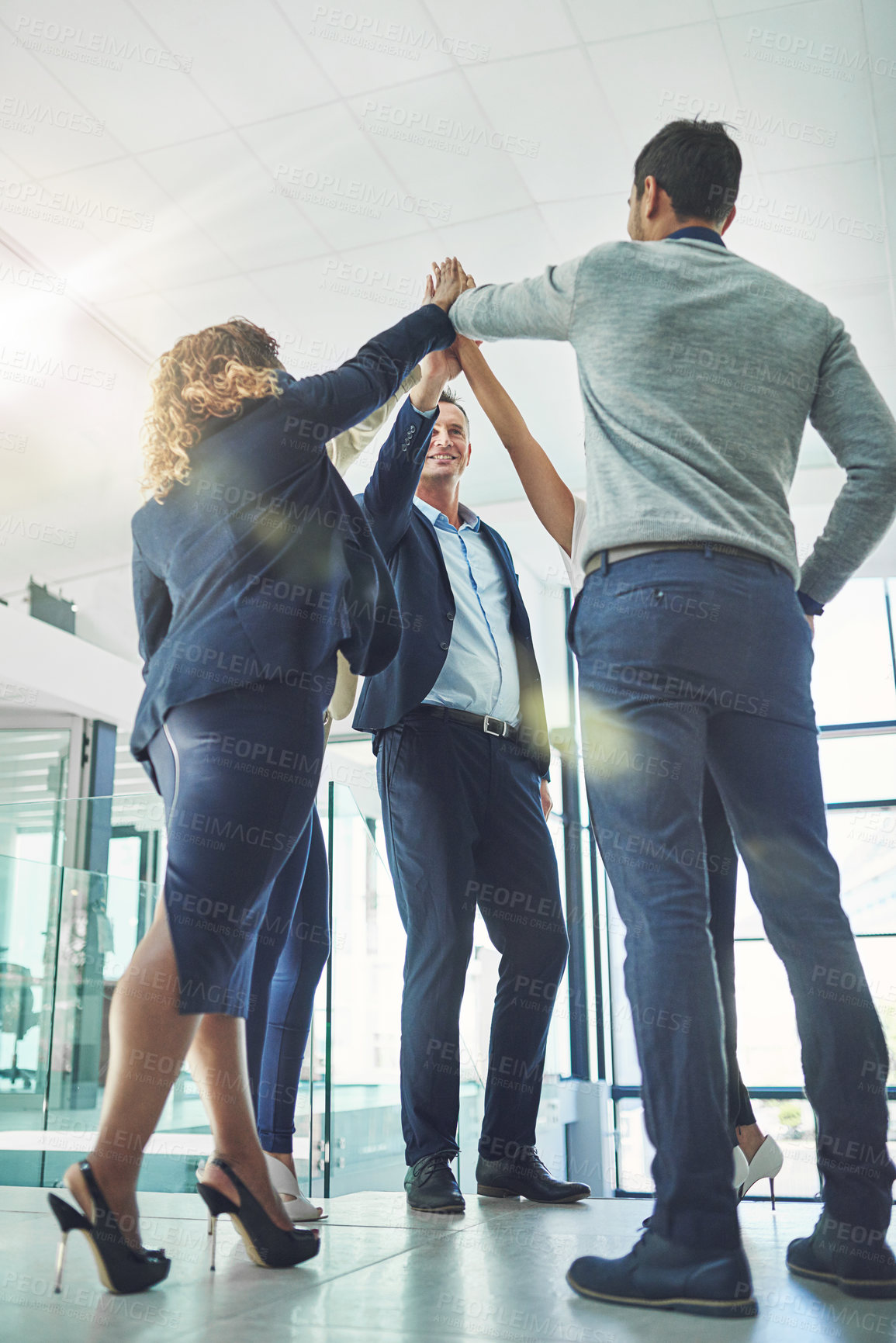 Buy stock photo Shot of a group of coworkers high fiving together in an office