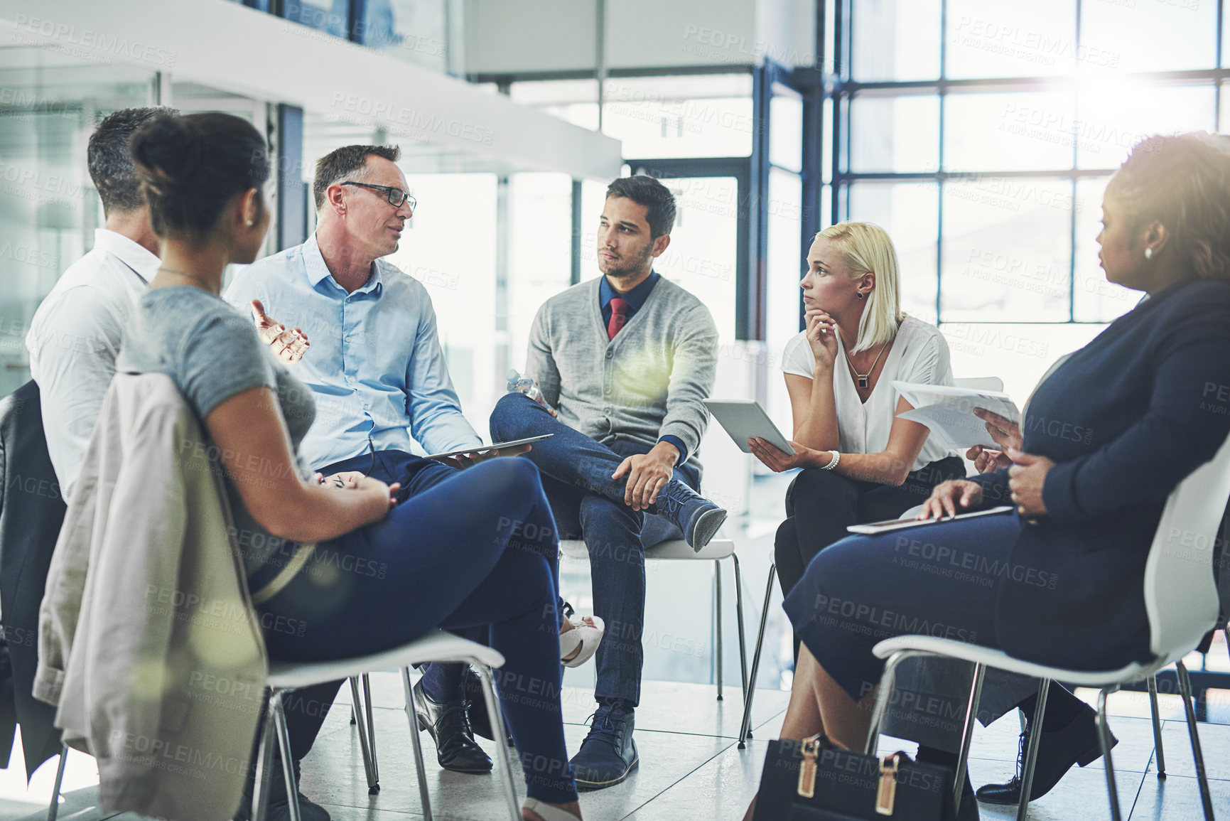 Buy stock photo Modern business people in an informal team building discussion or business talking session. Team leader, manager or supervisor talking to a group of employees or colleagues on new workflow management