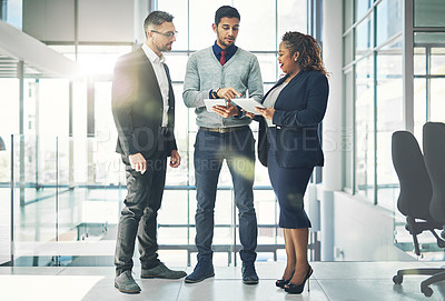 Buy stock photo Shot of a group of coworkers talking together over a digital tablet in an office