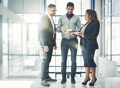 Buy stock photo Shot of a group of coworkers talking together over a digital tablet in an office