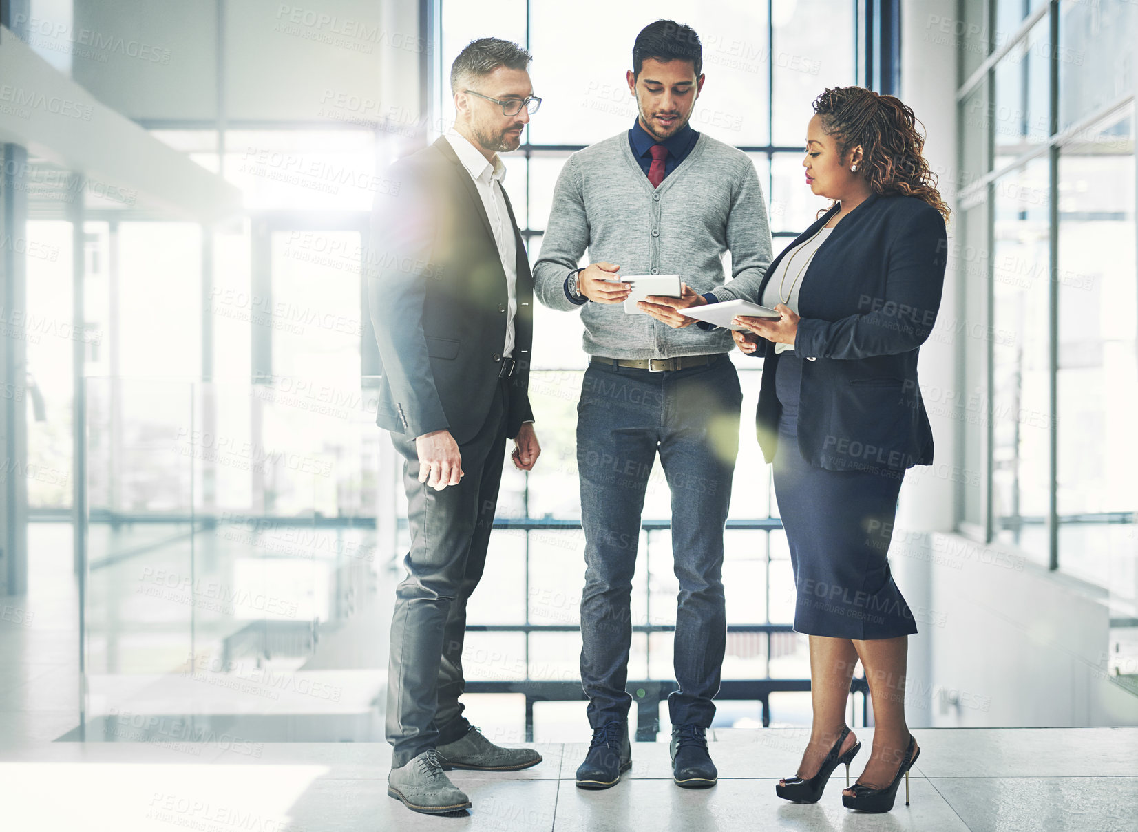 Buy stock photo Shot of a group of coworkers talking together over a digital tablet in an office