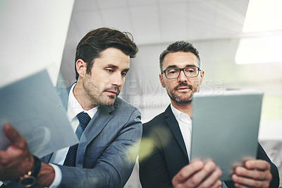Buy stock photo Shot of two coworkers talking together over a digital tablet in an office