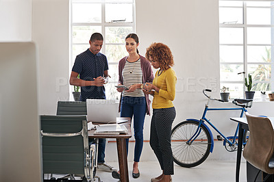Buy stock photo Shot of a group of colleagues having an informal meeting with a laptop in a modern office