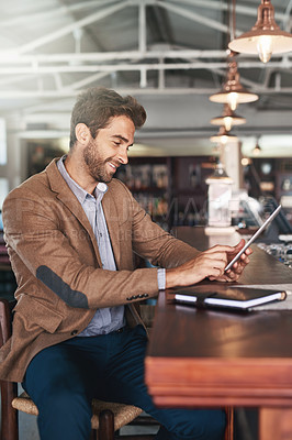 Buy stock photo Cropped portrait of a handsome young man using his digital tablet in a bar