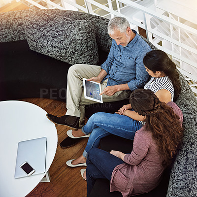 Buy stock photo High angle shot of three colleagues looking at a digital tablet
