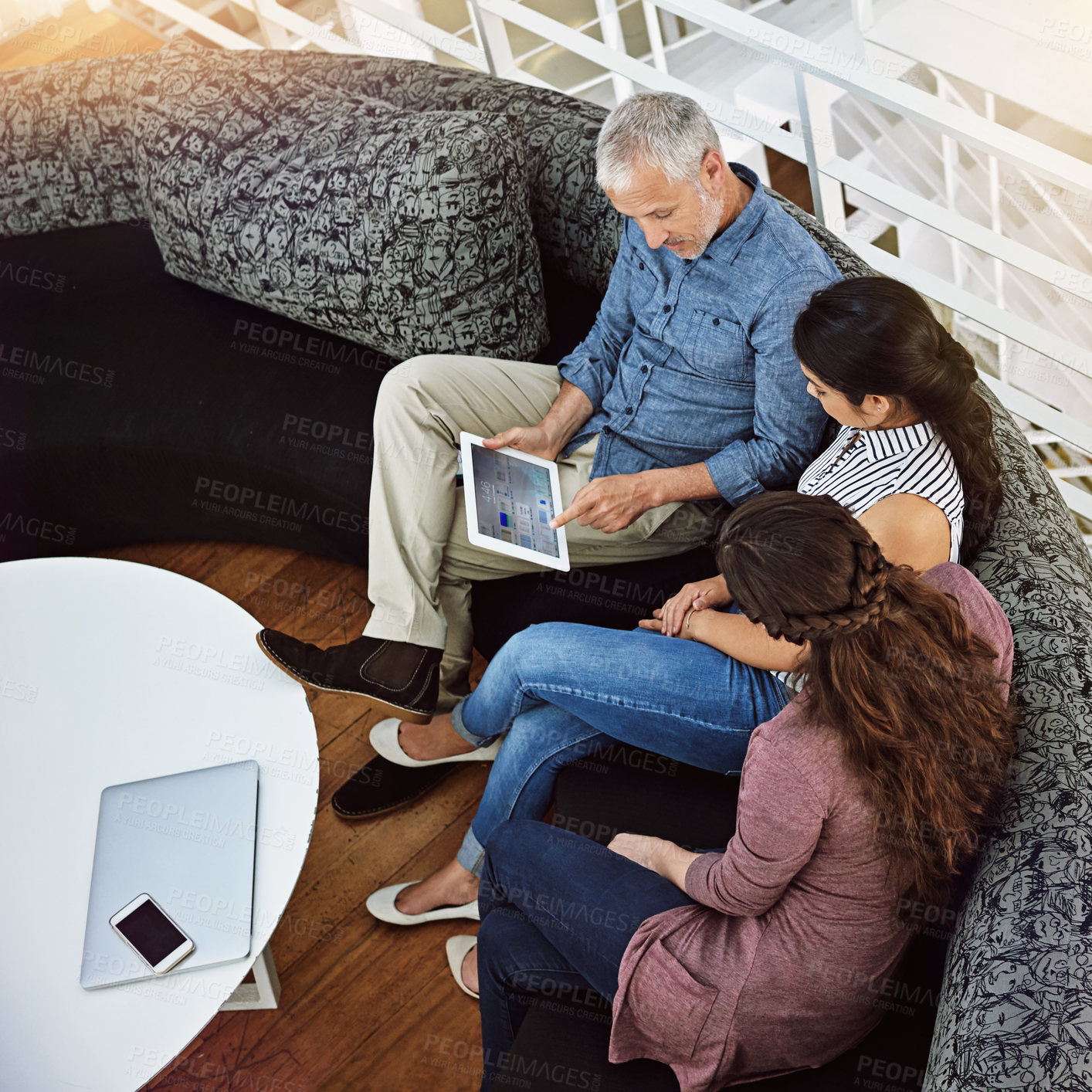 Buy stock photo High angle shot of three colleagues looking at a digital tablet