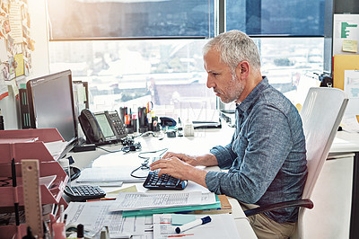 Buy stock photo Shot of a mature man at work on computer in an office