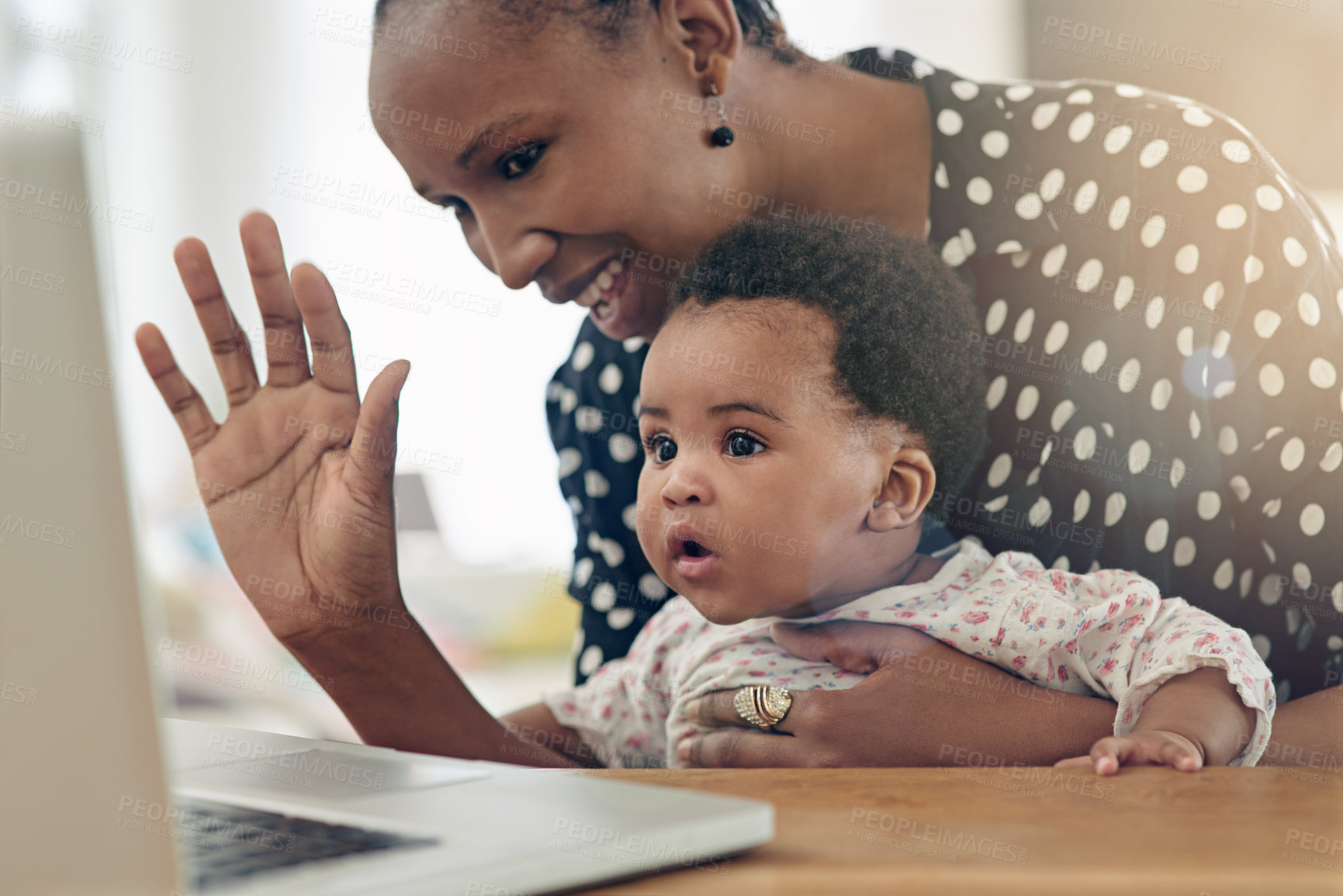 Buy stock photo Shot of a mother and her baby girl sitting in front of a laptop