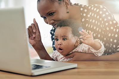 Buy stock photo Shot of a mother and her baby girl sitting in front of a laptop